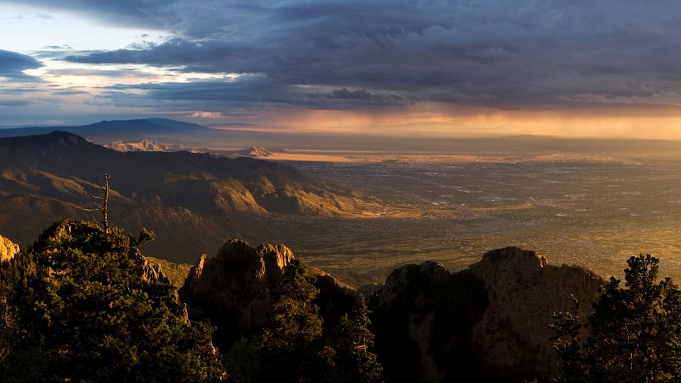 A mountainous landscape with a valley and a distant city.