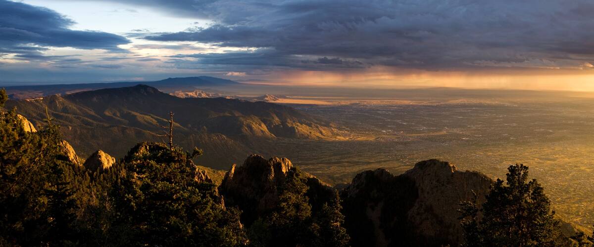 A mountainous landscape with a valley and a distant city.