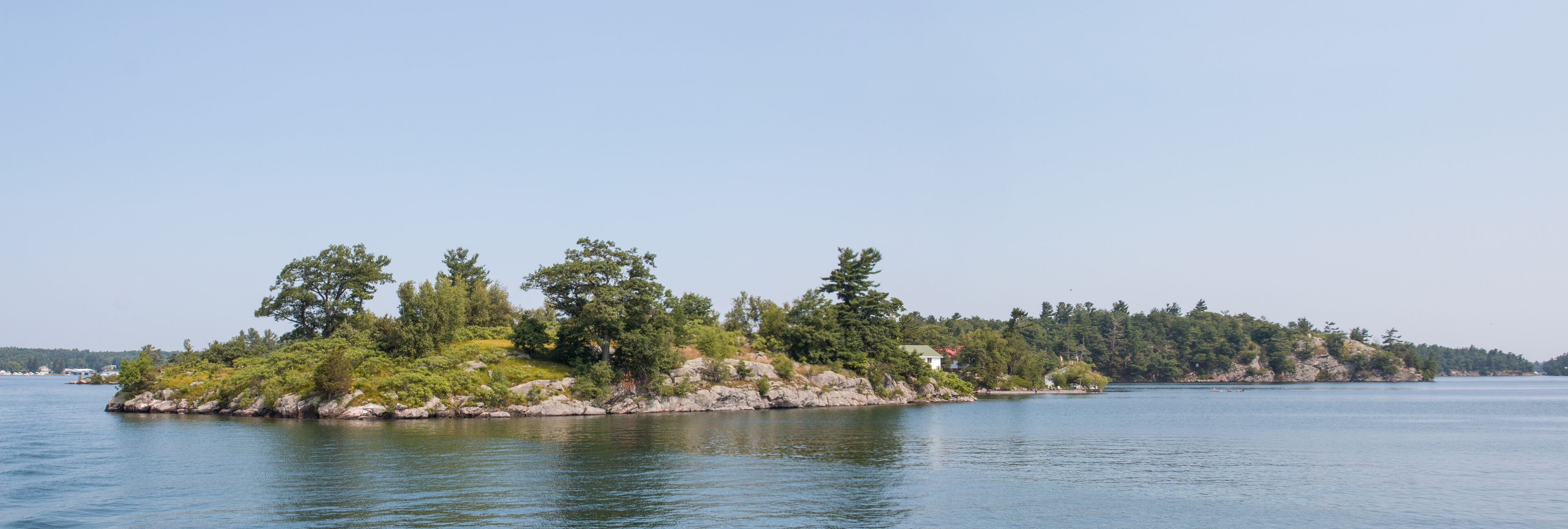 A small island with dense trees and a few buildings.