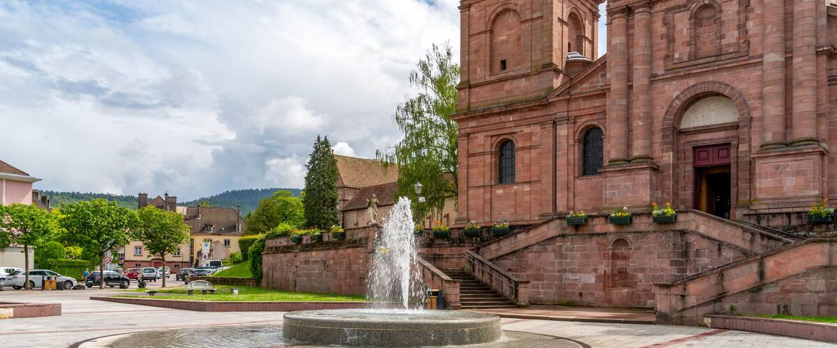 A historic church with a fountain in the center of a paved square.