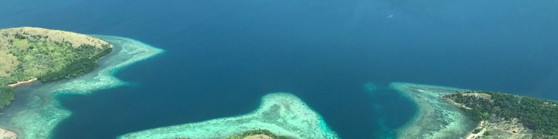 Vista aérea de uma cadeia de ilhas com águas azul-claras e lagoas turquesa.