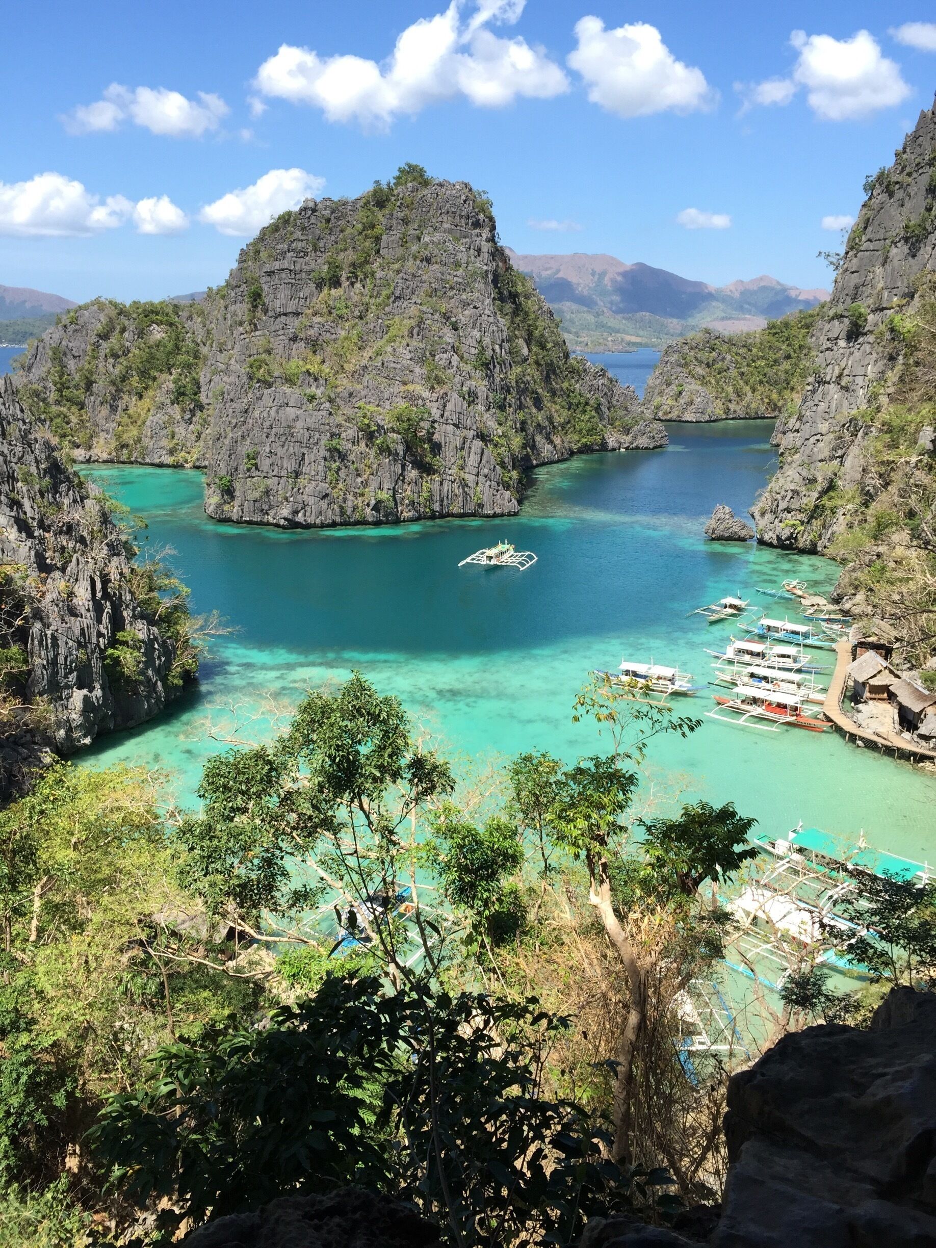 A coastal landscape with rocky cliffs, clear turquoise waters, and traditional boats.
