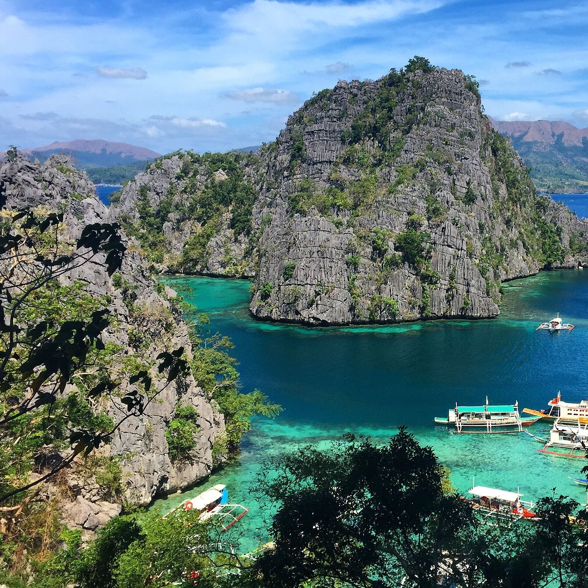 A mountainous landscape with clear turquoise waters and boats.