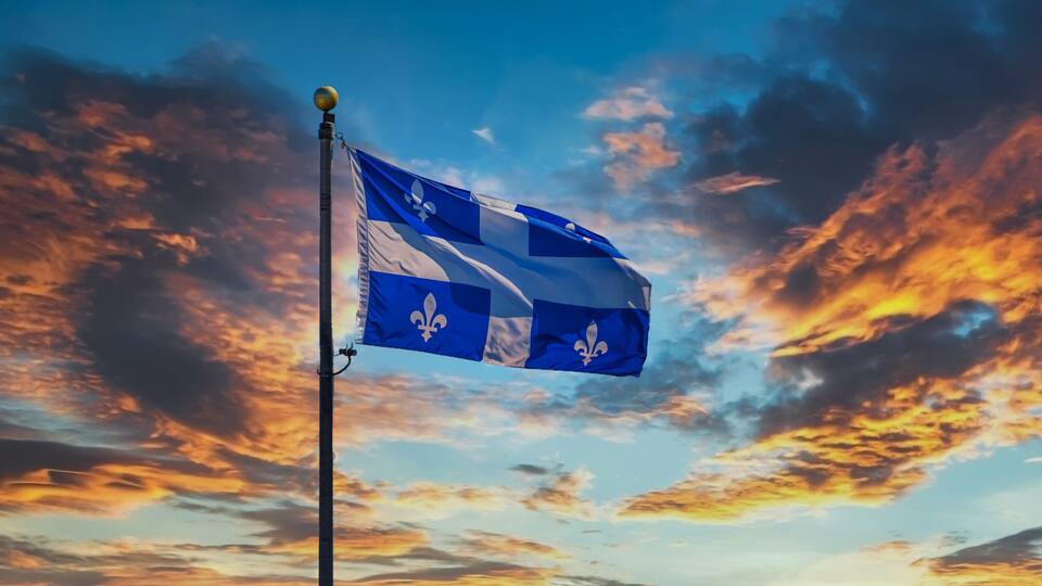 A flag on a pole against a sunset sky.