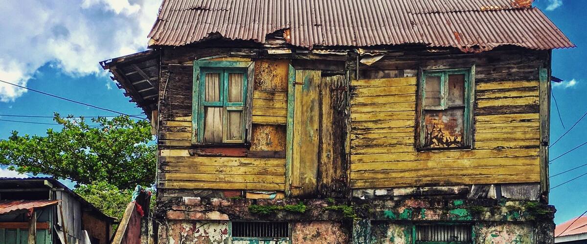 Outside of the centre of Roseau kid cruising by a house that seems desolated. When I wanted to look inside it turned out to be occupied and man was watching tv.