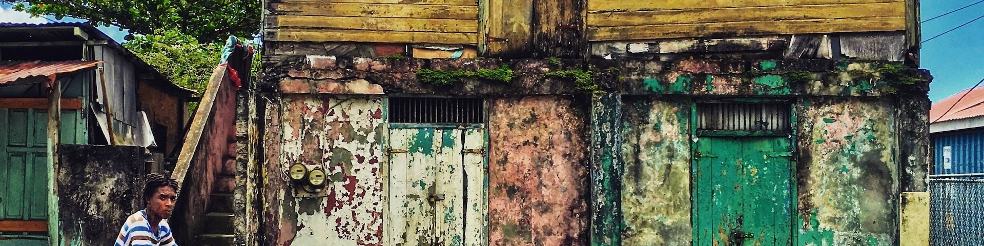 Outside of the centre of Roseau kid cruising by a house that seems desolated. When I wanted to look inside it turned out to be occupied and man was watching tv.