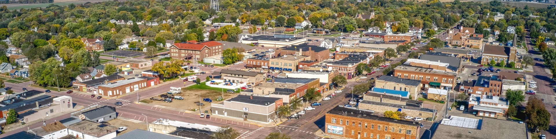 An aerial view of a small town with a mix of residential and commercial buildings, a prominent water tower, and a church steeple.