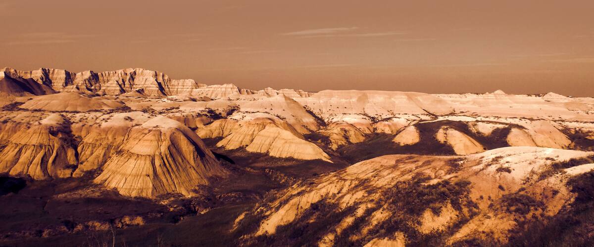 A vast landscape of eroded rock formations with distinct layers and a river cutting through the terrain.
