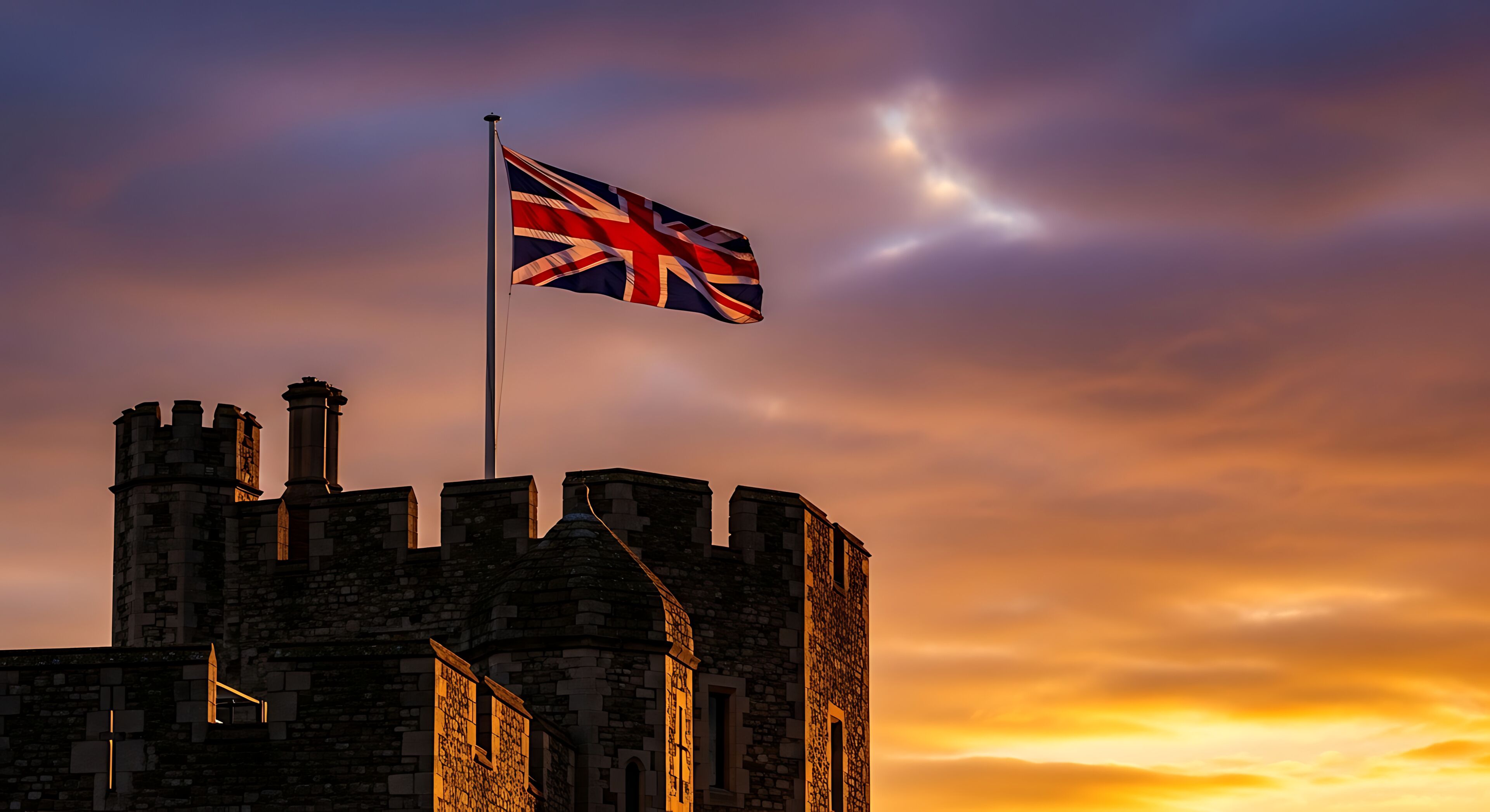 The union jack flag flying over the historic windsor castle at sunset