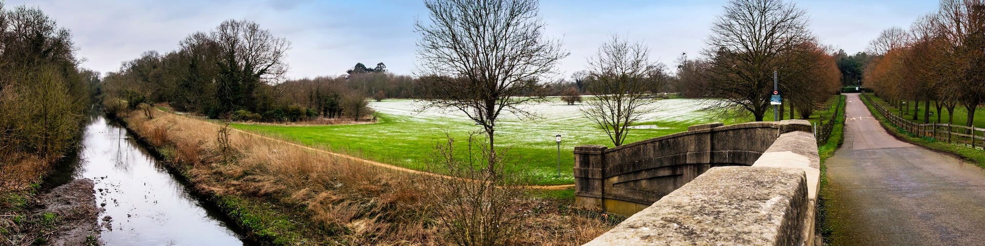 Panoramic view of Cranford Park and river Crane after a mild snowfall in March.