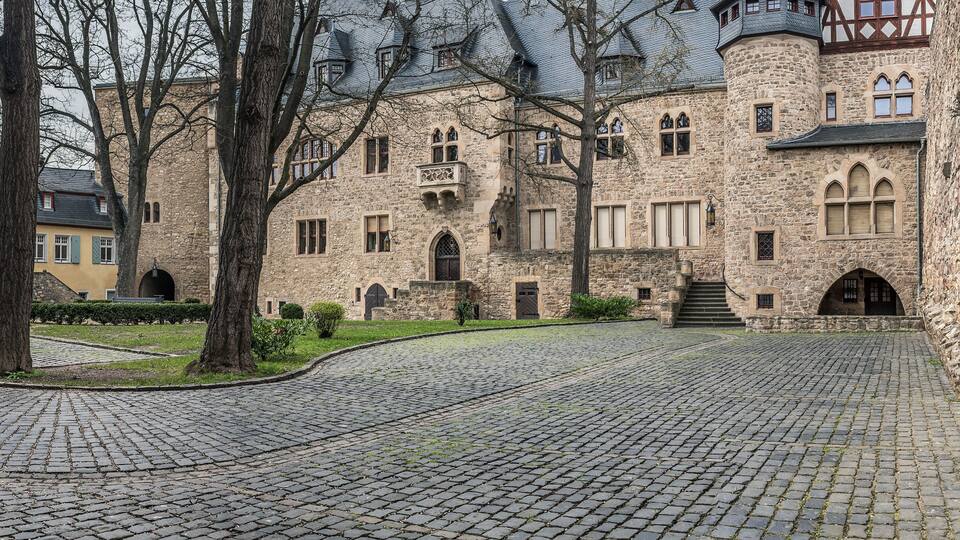 A historic stone building with arched windows and a cobblestone courtyard.