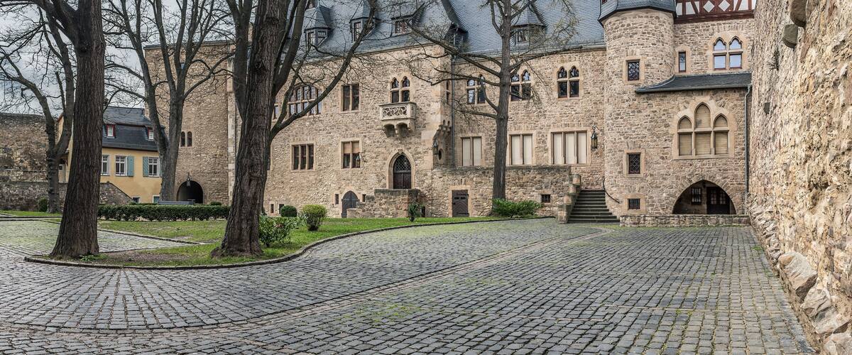 A historic stone building with arched windows and a cobblestone courtyard.