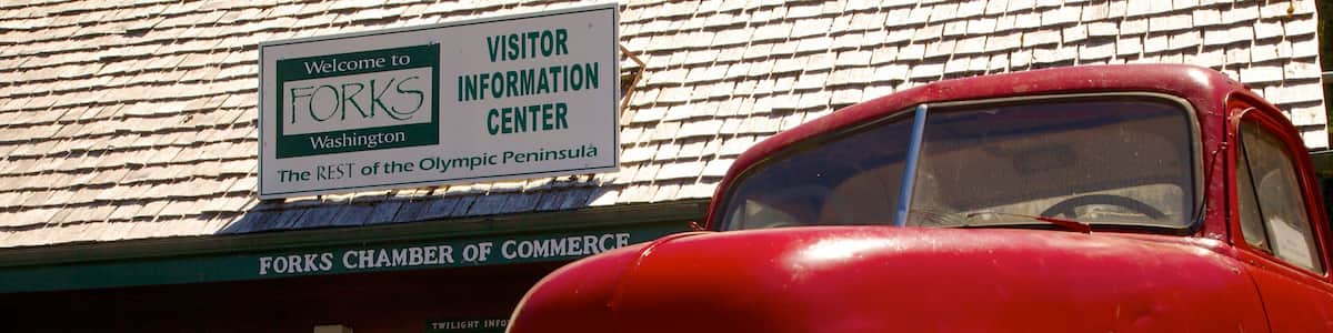 Ein roter Oldtimer parkt vor einem Gebäude mit dem Schild "Welcome to FOKS Visitor Information Center".