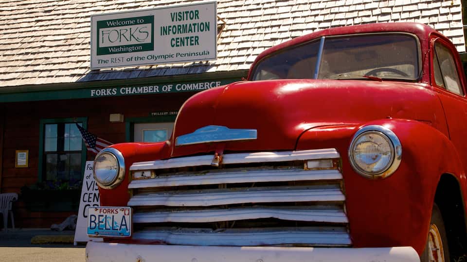 A red vintage car parked in front of a building with a sign reading "Welcome to FOKS Visitor Information Center".