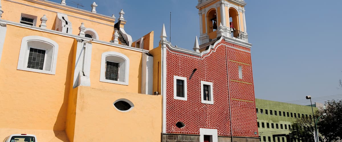 A yellow building with a red brick tower and a bell tower.