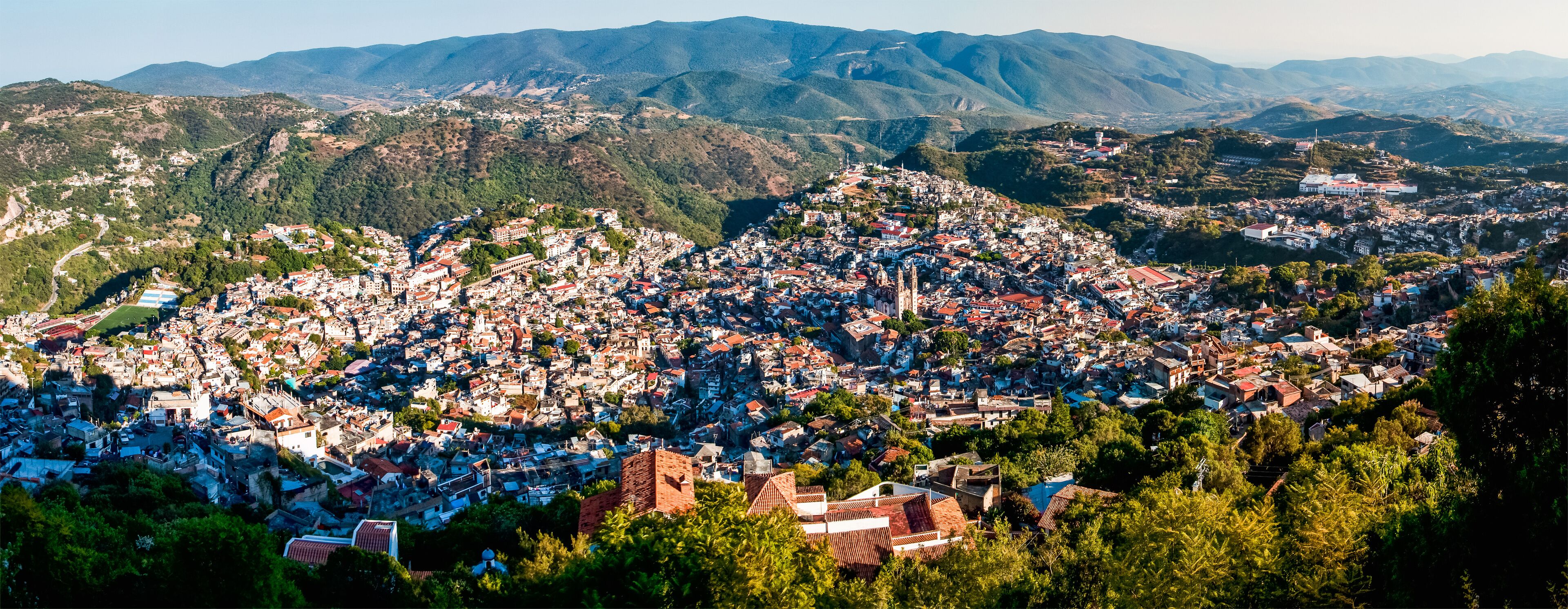 A densely populated town nestled in a valley with mountains in the background.
