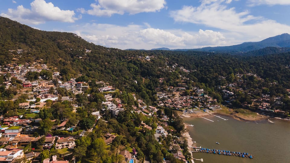 A coastal town with dense housing, a beach, and mountains in the background.