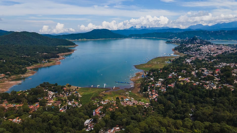 A coastal town with a large lake surrounded by mountains.