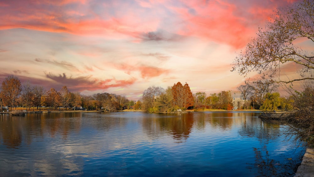 A lake with autumn trees, a clear sky, and a distant building.