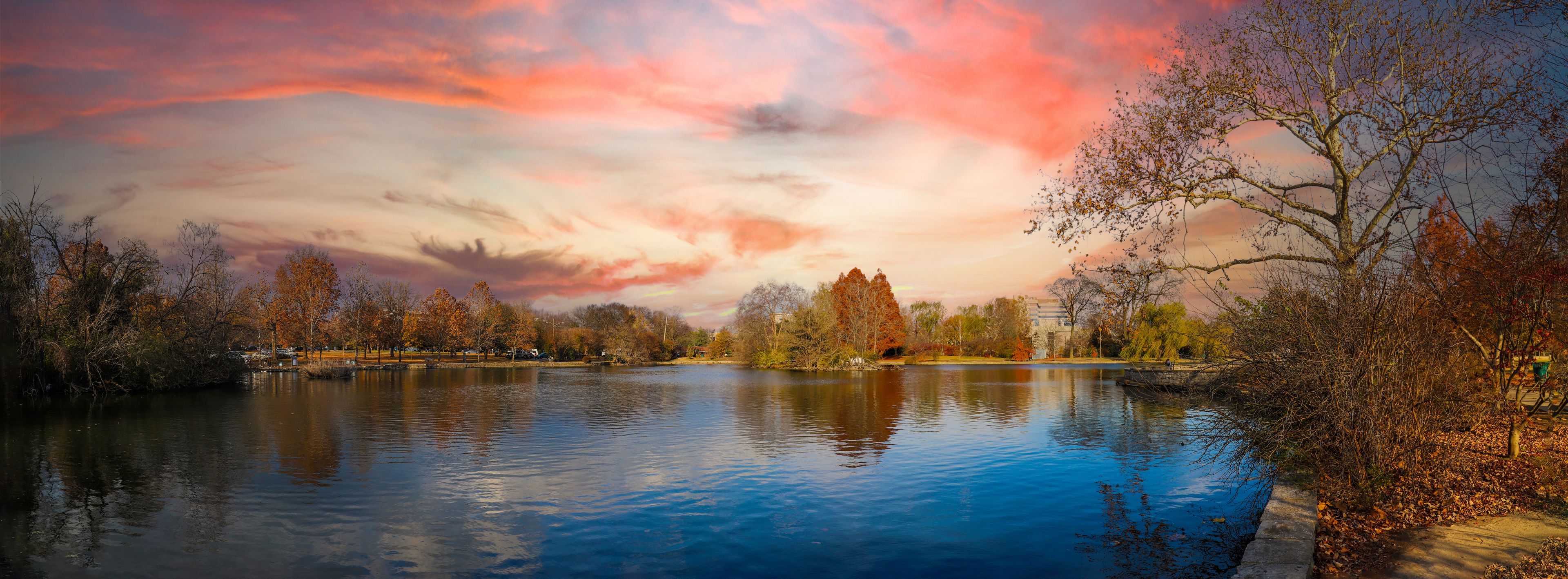 A lake with autumn trees, a clear sky, and a distant building.