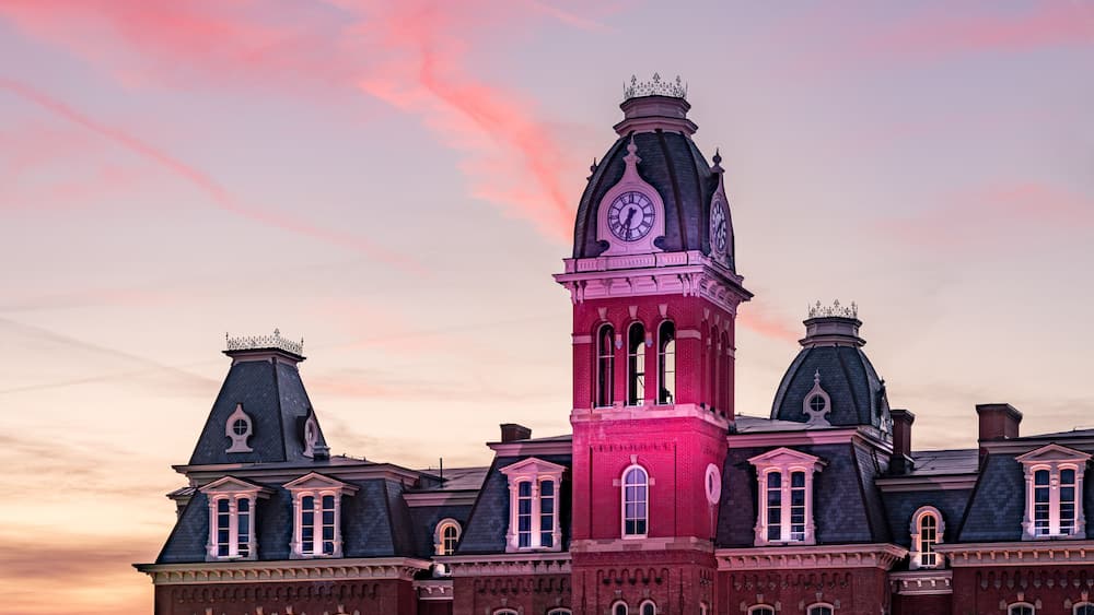 Dramatic image of Woodburn Hall at West Virginia University or WVU in Morgantown WV as the sun sets behind the illuminated historic building