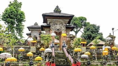 Um templo com uma escadaria central, esculturas elaboradas e vários guarda-sóis amarelos.