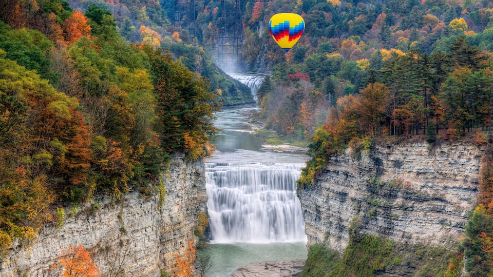 A waterfall cascading down a cliff surrounded by autumn foliage.