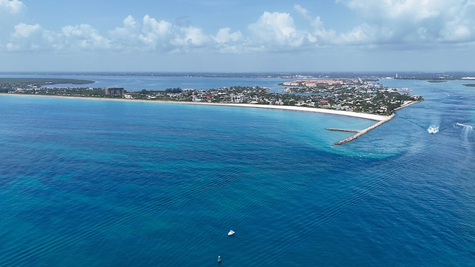 A coastal town with a beach, clear blue waters, and a distant island.