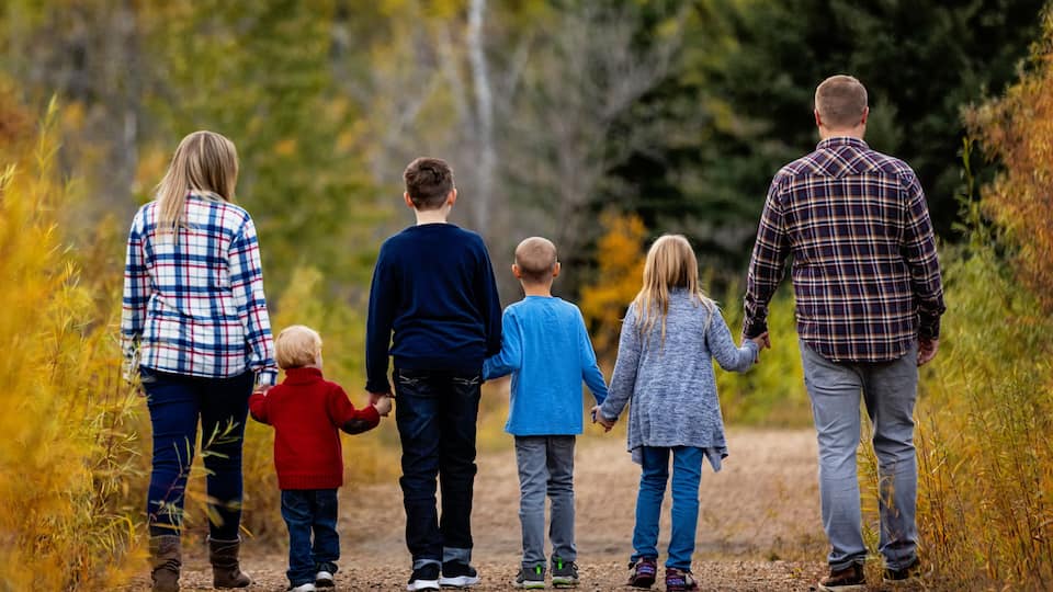 A family walking on a dirt path surrounded by autumn foliage.