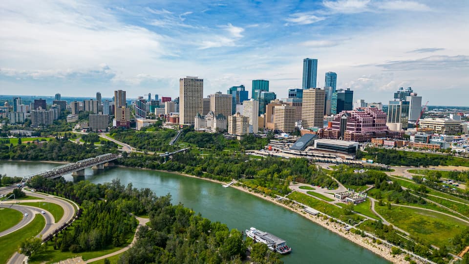 A city skyline with modern skyscrapers, a river, and a bridge.