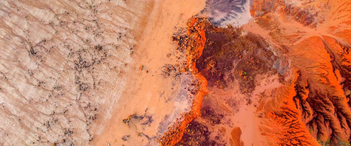 A rugged landscape with varied terrain, including sandy areas, rocky outcrops, and patches of vegetation.
