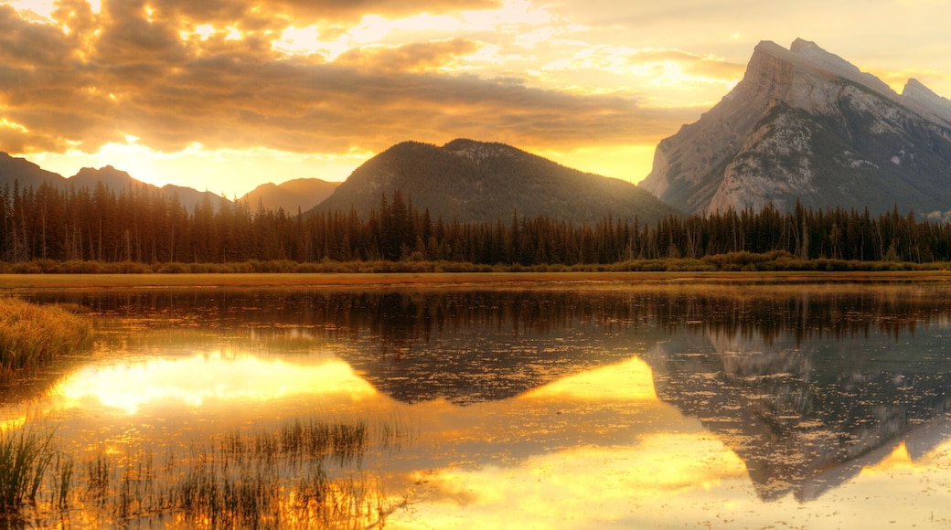Una cordillera con un lago que refleja el paisaje y colinas cubiertas de bosque.