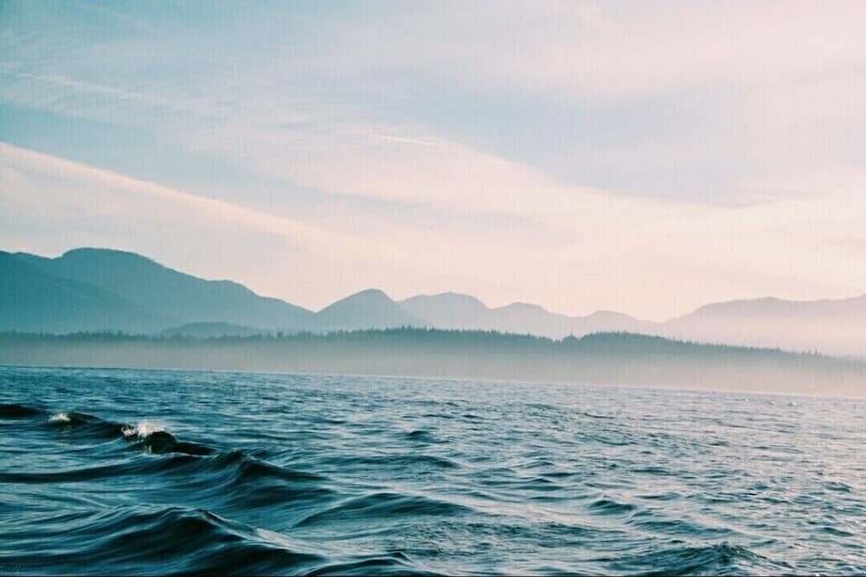 A calm lake with mountains in the background.