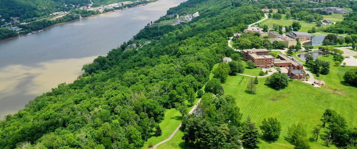 A river winding through a densely forested area with buildings and open fields.