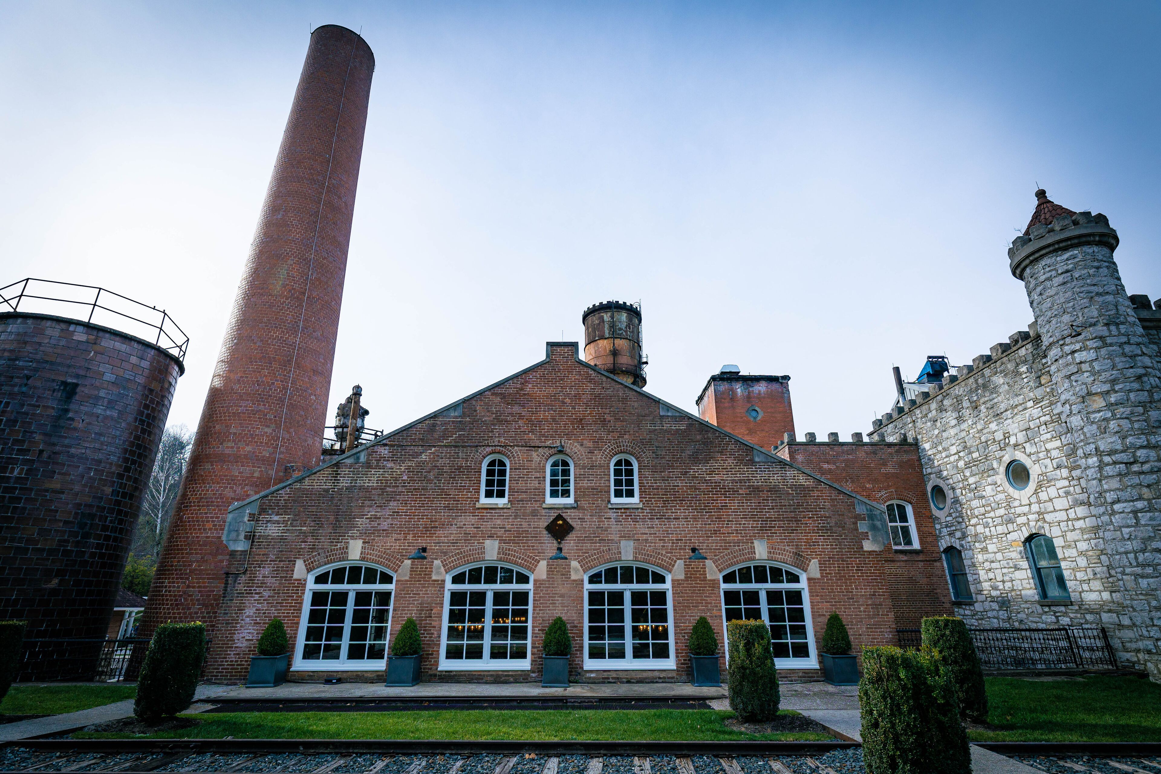 Industrial building in a factory with a chimney and railroad tracks in front of it. Bourbon distillery in rural Kentucky close to the capital city of Frankfort.