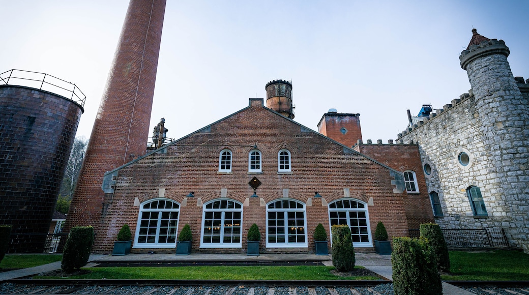 Industrial building in a factory with a chimney and railroad tracks in front of it. Bourbon distillery in rural Kentucky close to the capital city of Frankfort.