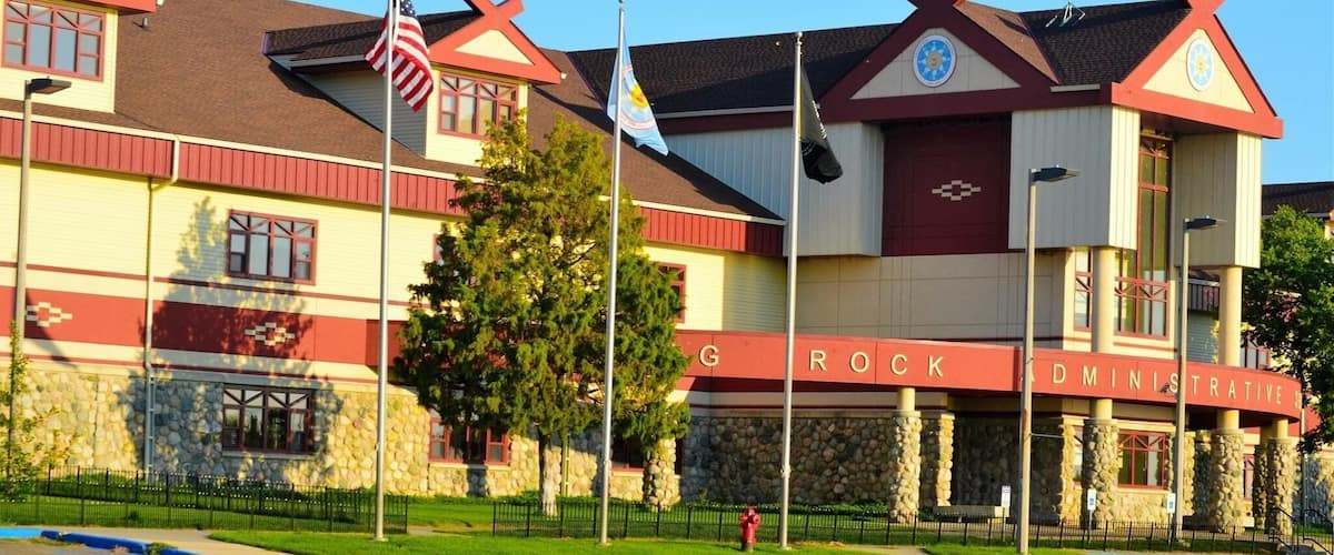 A building with a red and white facade, a stone wall, and flags.