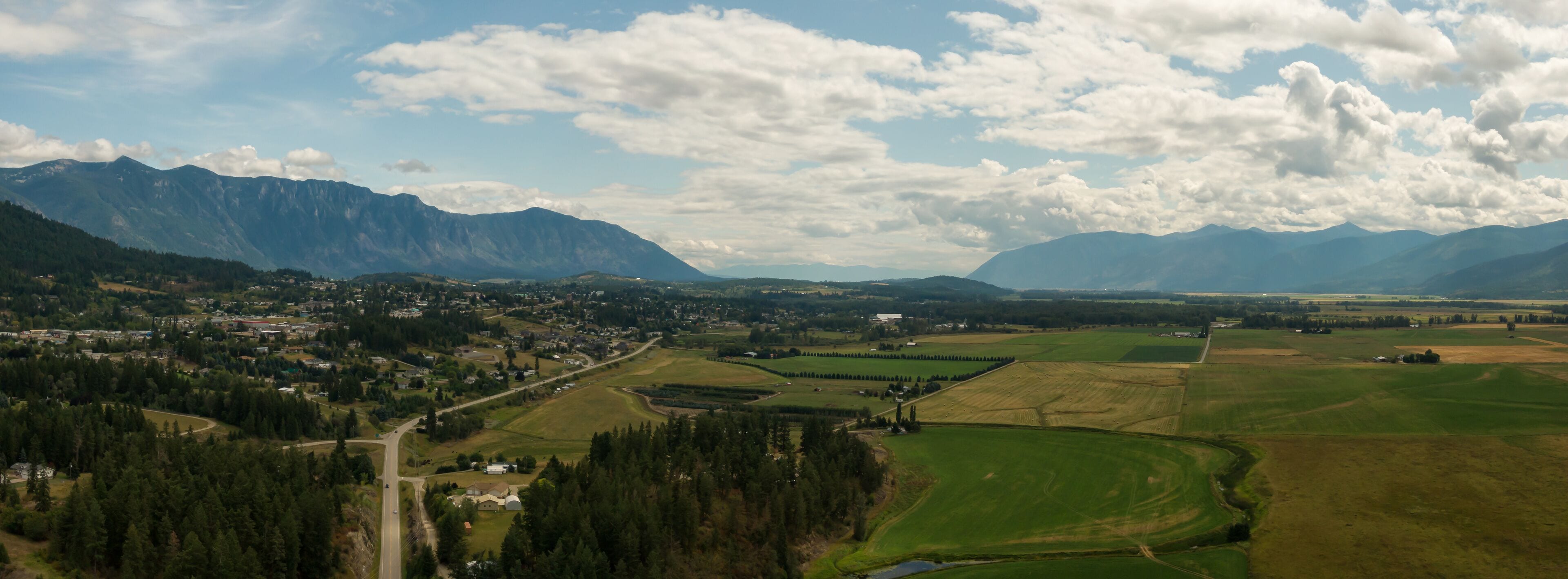 Aerial Panoramic View of Small Town, Creston, during a sunny and cloudy summer day. Located in the Interior of British Columbia, Canada.