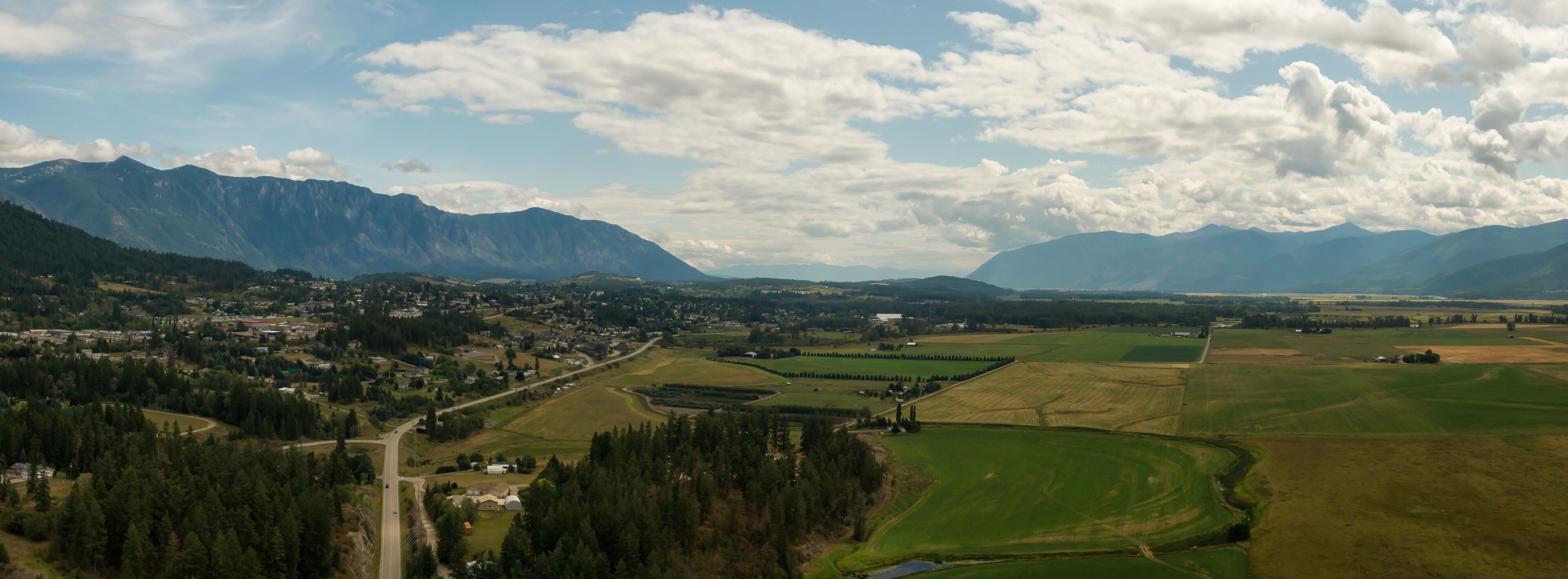 A mountainous landscape with a town nestled among rolling hills and fields.