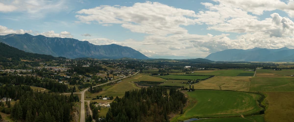 A mountainous landscape with a town nestled among rolling hills and fields.