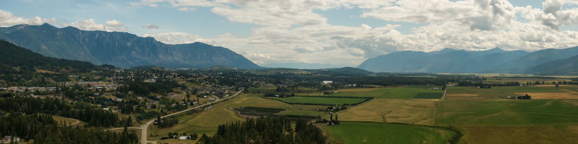 A mountainous landscape with a town nestled among rolling hills and fields.