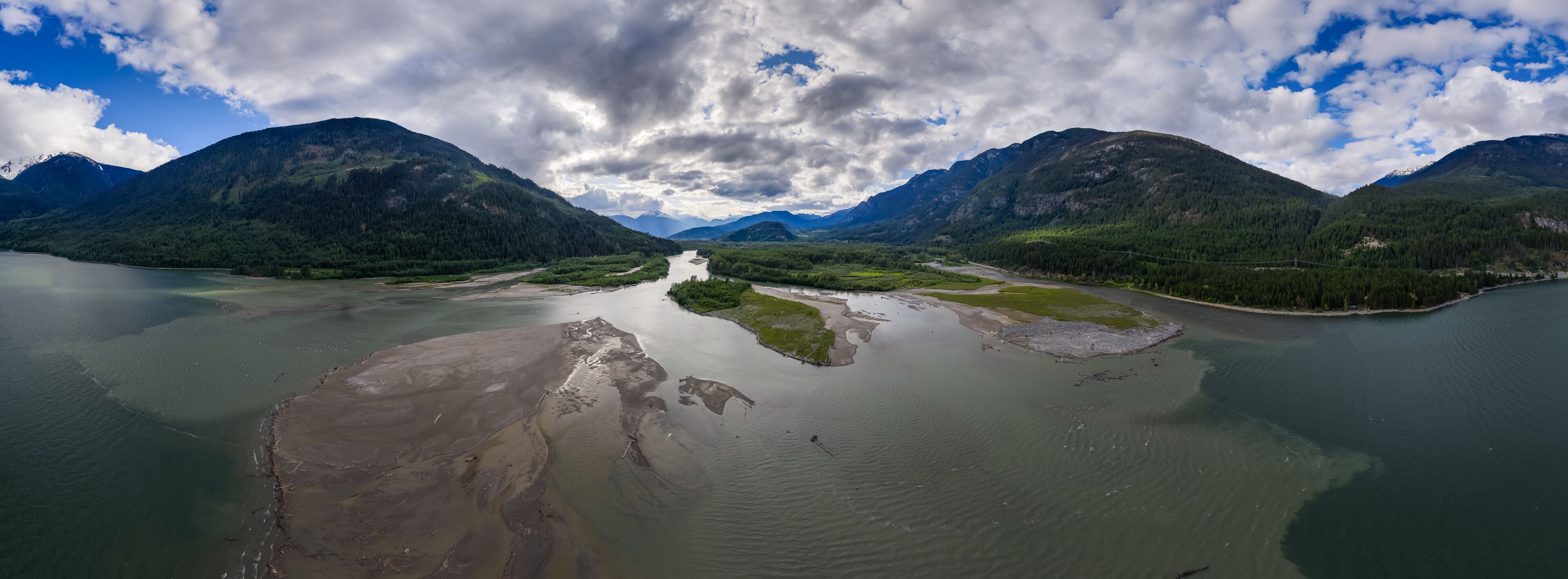 Aerial View of Majestic River and Forested Mountains Under Blue Skies