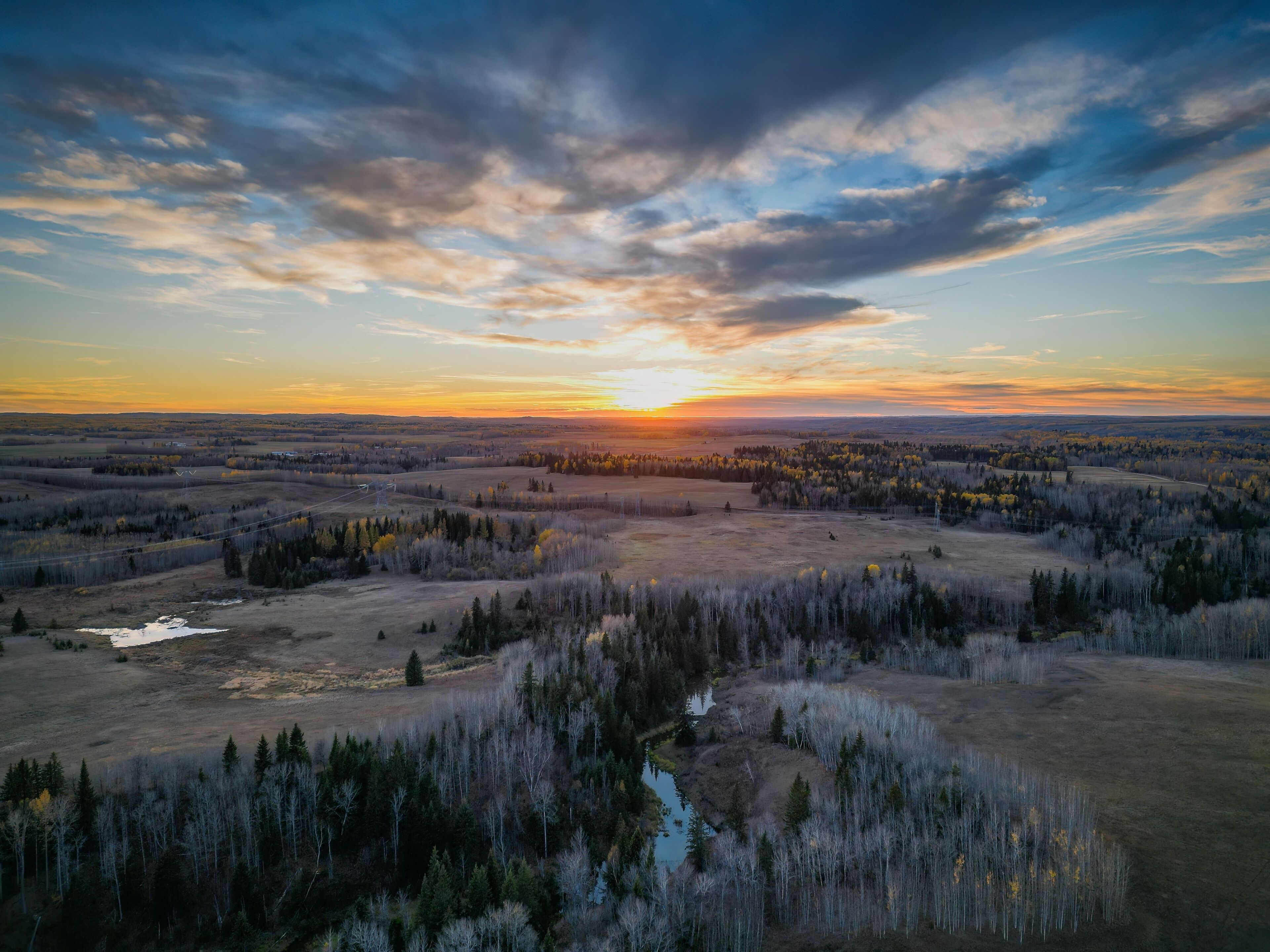 Un paisaje extenso con un río, un bosque denso y un atardecer.