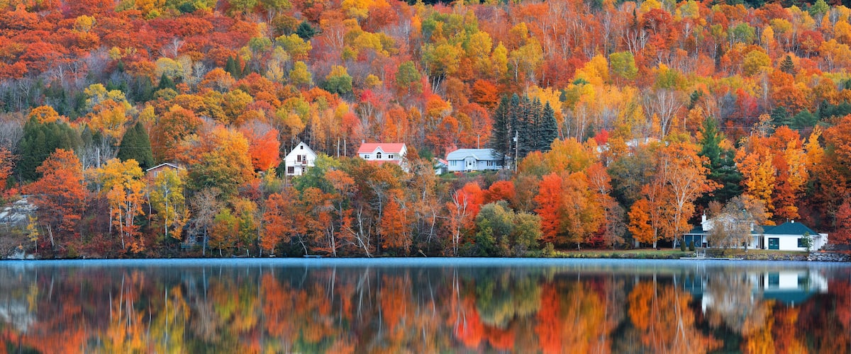 A lake surrounded by autumn-colored trees and houses on a hillside.