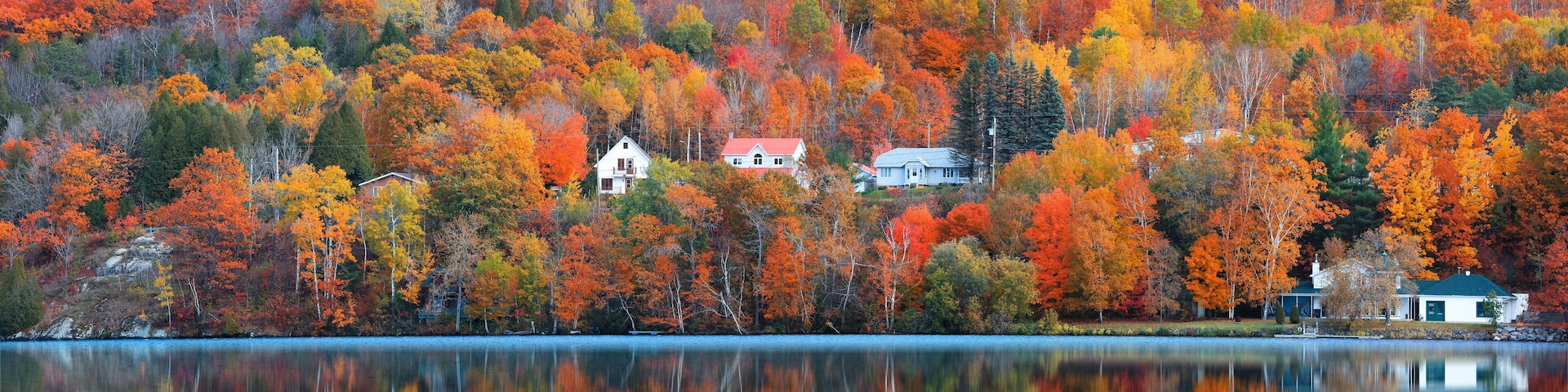 A lake surrounded by autumn-colored trees and houses on a hillside.
