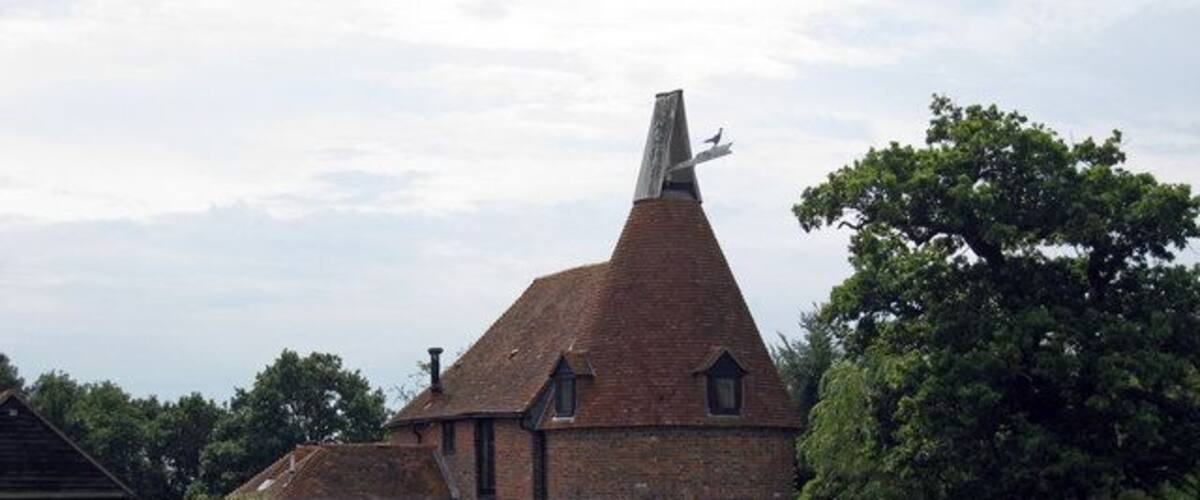 A brick church with a conical roof in a rural setting.