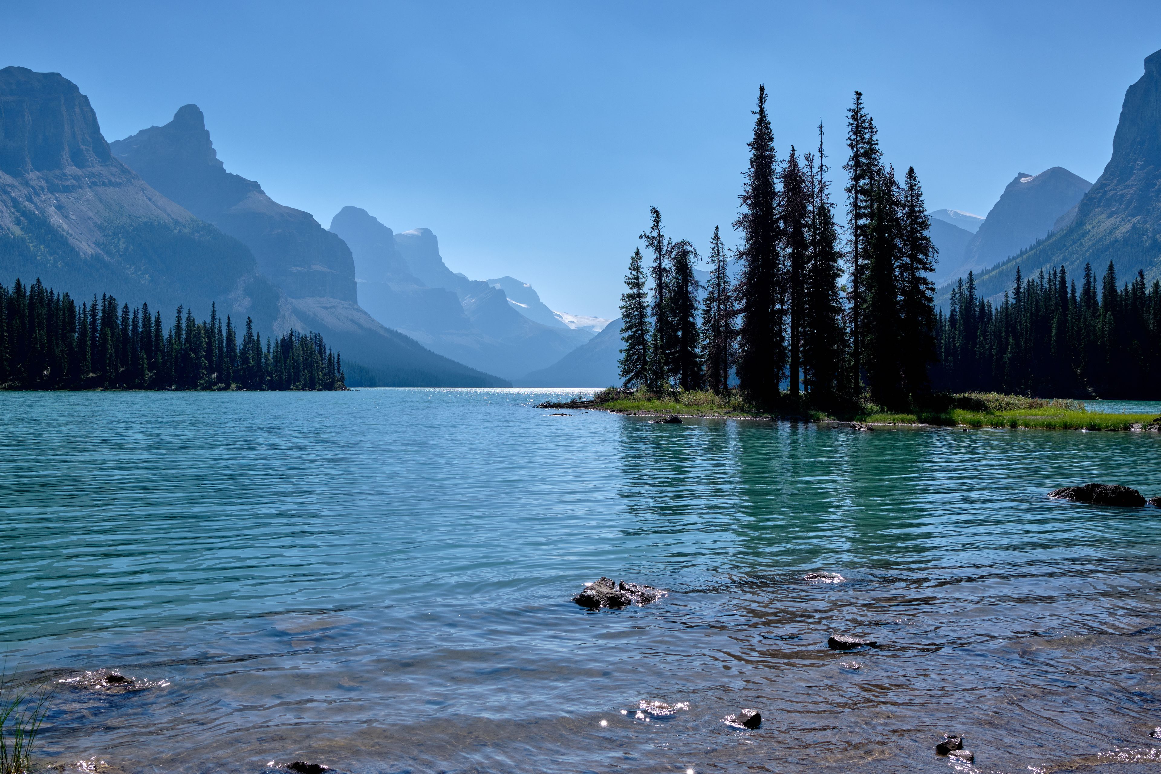 A calm lake surrounded by mountains and dense forests.