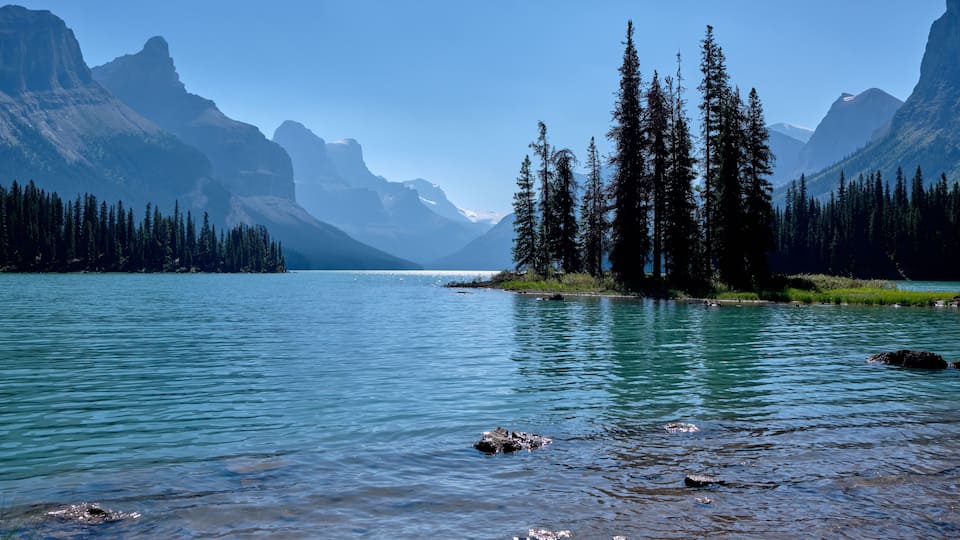 A calm lake surrounded by mountains and dense forests.