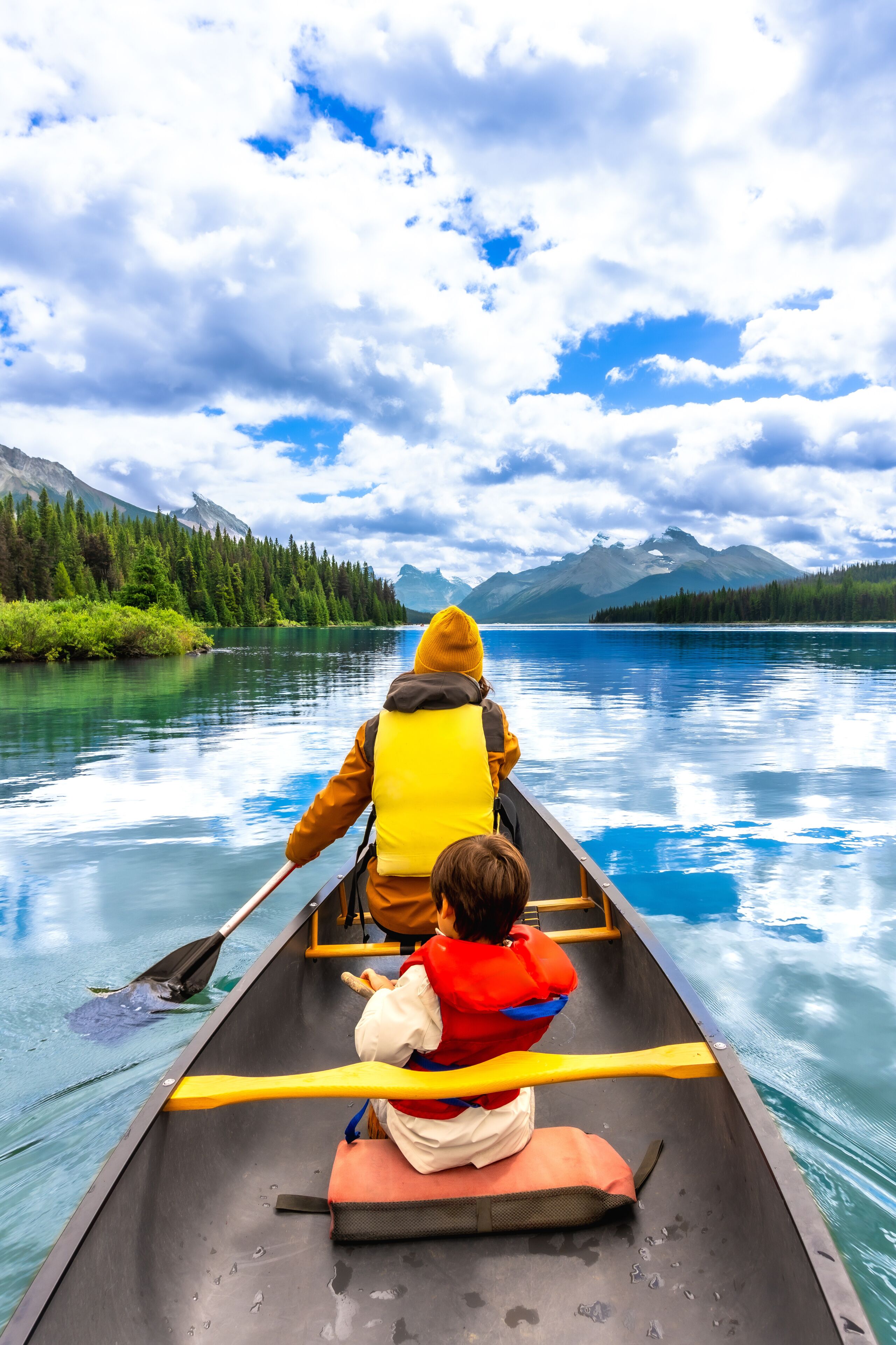 A canoe on a calm lake with mountains in the background.