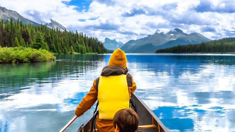 A canoe on a calm lake with mountains in the background.